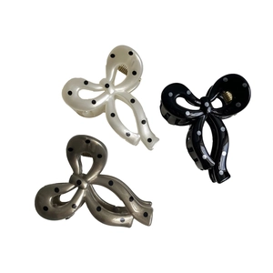 Polka dot bow hair clips in beige, black, and grey with gold metal springs