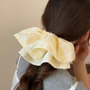 Yellow gingham oversized scrunchie hair tie with pleated bow design on a model