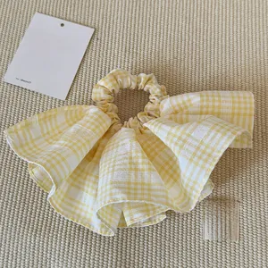 Detail shot of yellow and white gingham large scrunchie on woven fabric background