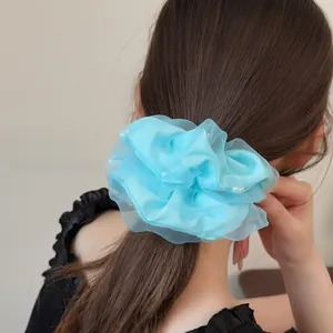 Detail eines hellblauen Haargummis aus Netzstoff mit eleganten weißen Perlen für Damen