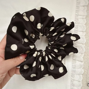 Polka dot oversized satin scrunchie held in hand showing soft texture and high elasticity