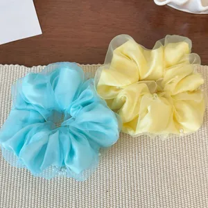 Detail von hellblauen und gelben Netz-Haargummis mit eleganten Perlen-Applikationen