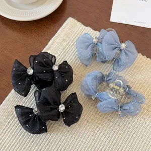 Close-up of dual organza bow hair claws with rhinestones in black and light blue colors