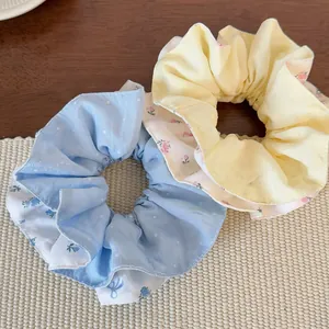 Nahaufnahme von Blumen-Scrunchies in Blau und Gelb mit feinen Faltenstoff-Details