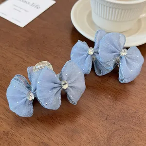 Light blue mesh bow hair claw clip with rhinestones and white polka dots on a desk