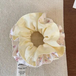 Detail eines doppellagigen Blumen-Haargummis mit gelben Punkten und rosa Blütenmuster