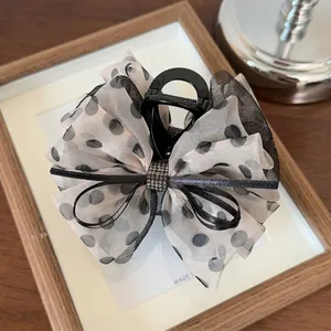 Détail de la grande pince à cheveux avec un nœud en tulle à pois et boucle en strass