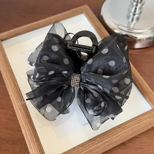 Détail d'une pince à cheveux en tulle noir à pois avec centre en strass étincelants