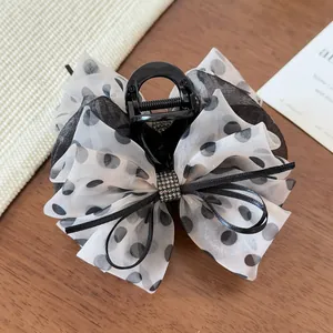 Détail de la pince à cheveux élégante avec nœud en tulle à pois et décor en cristal