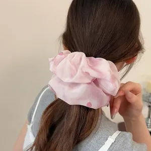 Elastico per capelli in organza rosa a pois mostrato su uno chignon sotto luce soffusa