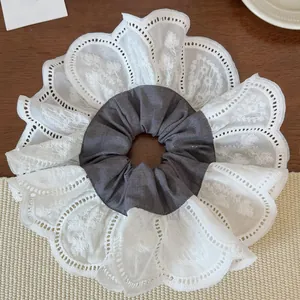 Detail view of large plaid fabric scrunchie with layered white lace embroidery edge
