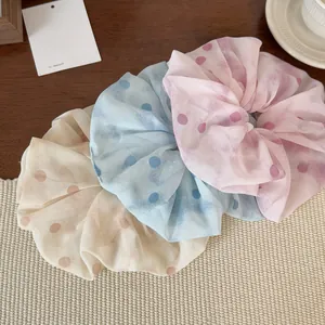 Dettaglio di eleganti elastici per capelli a pois in rete beige blu e rosa su stuoia