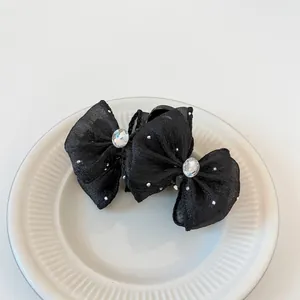 Elegant double mesh bow hair clips with white pearls and rhinestones on a white plate