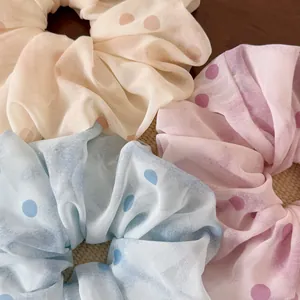 Dettaglio di elastici scrunchie in chiffon semitrasparente a pois con texture a pieghe
