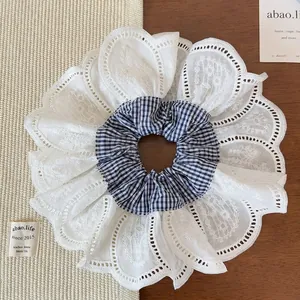 Macro shot of oversized blue plaid scrunchie with layered white lace embroidery and fabric detail