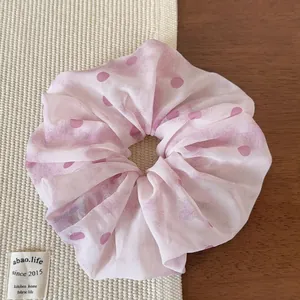 Dettaglio dell'elastico per capelli in chiffon a pois rosa con morbida trama a pieghe
