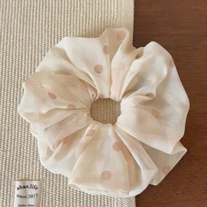 Dettaglio dell'elastico in tulle beige a pois rosa su una superficie di tessuto morbido