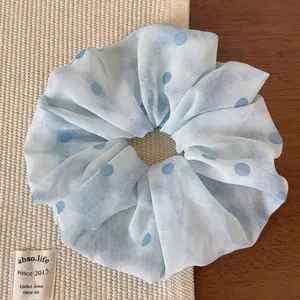Dettaglio dell'elastico in rete azzurra con pois blu scuro su un tappeto intrecciato