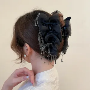 Detail of elegant black ribbon bow hair claw with sparkling rhinestone tassels for women