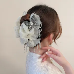 Detailed view of luxury bow hair clip with organza petals and rhinestone butterfly tassel