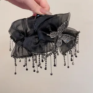 Detail of elegant black organza bow hair claw with sparkling rhinestone long tassels