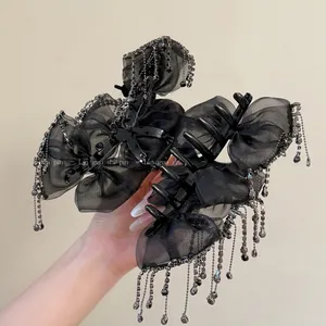 Detail of elegant black mesh bow hair claw with rhinestones and long metallic chain tassels