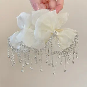 Close-up of white organza bow hair claw clip with cascading silver rhinestone tassels
