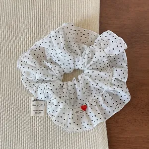 Gros plan sur chouchou blanc à pois noirs avec étiquette faite main et bouton cœur