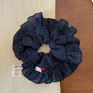Détail d'un chouchou bleu marine à pois avec tulle et petit charme en cœur rouge