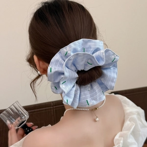 Forest style blue plaid scrunchie with white flower embroidery on a low bun hairstyle