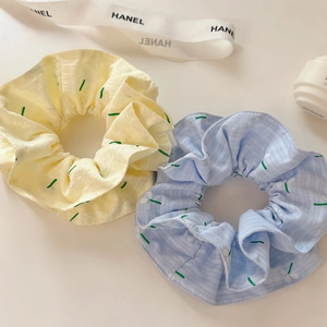 Close-up of floral scrunchies in lemon yellow and sky blue with textured plaid fabric