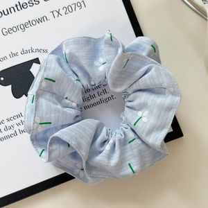Detail of light blue floral scrunchie with white daisy print on soft textured fabric