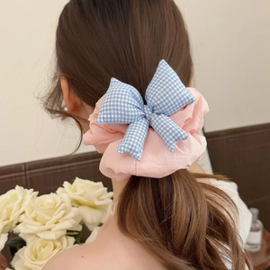 Detailed view of a large pink ruffled scrunchie with a blue checkered 3D bow on hair