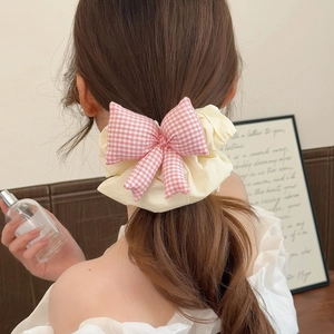 Pink checkered bow scrunchie on low ponytail hair accessory for women stylish look