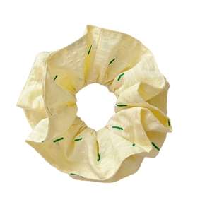 Pale yellow forest style scrunchie with white dots and green bud patterns for hair