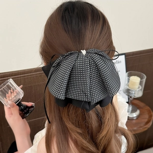 Detail of polka dot mesh bow hair clip with double pearl accents on brown hair