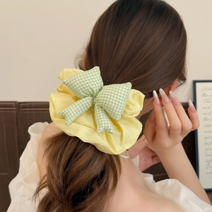 Detail of yellow ruffled scrunchie with green checkered bow in a high ponytail hairstyle
