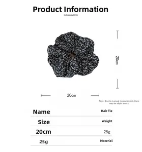 Gros plan du chouchou en tissu noir avec motif floral blanc sur fond blanc pur