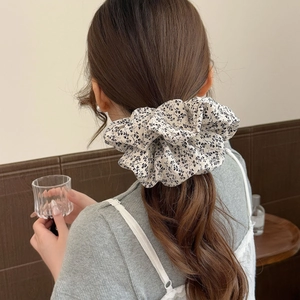 Chouchou en tissu à imprimé fleuri porté sur les cheveux en chignon élégant