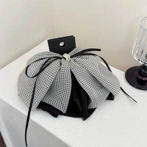Detail of a large mesh dot bow hair clip with pearl embellishments and black ribbon