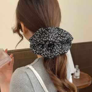 Chouchou floral noir et blanc élégant présenté dans une coiffure en queue de cheval basse