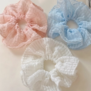 Trois chouchous géants en seersucker rose, bleu et blanc avec textures à volants plissés