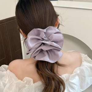 Dettaglio di un grande elastico in chiffon viola su un'acconciatura a coda di cavallo