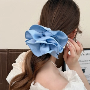 Elegante elastico per capelli azzurro con volant oversize su una coda di cavallo bassa