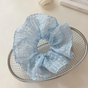 Gros plan sur chouchou en organza à carreaux bleu clair avec volants dans un panier en métal
