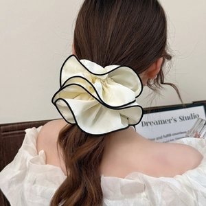 Dettaglio dell'elastico scrunchie crema con bordo nero su coda di cavallo alta