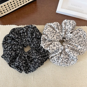 Gros plan de chouchous floraux en tissu noir et blanc sur un tapis de texture