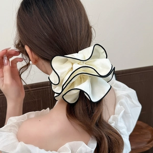 Elegante elastico in raso crema con bordo nero indossato su una coda di cavallo