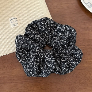 Texture détaillée d'un chouchou en tissu à fleurs noir et blanc sur fond bois