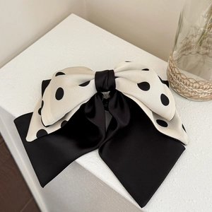 Close-up of a French style large bow hair claw clip with black polka dots and satin layers